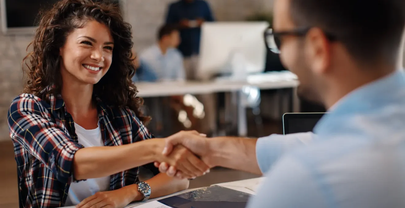 Professionnels collaborant autour d'une table haute dans un bureau moderne en Suisse, discutant activement d'un projet dans un espace de travail lumineux