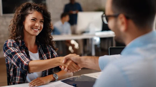 Professionnels collaborant autour d'une table haute dans un bureau moderne en Suisse, discutant activement d'un projet dans un espace de travail lumineux